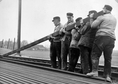 222774 Afbeelding van baanwerkers van de N.S. tijdens het verplaatsen van een spoorstaaf, vermoedelijk tijdens de ...